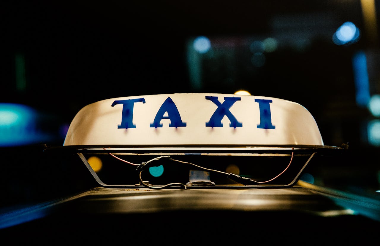 hero-img-02 Close-up view of an illuminated taxi sign in a bustling city at night.